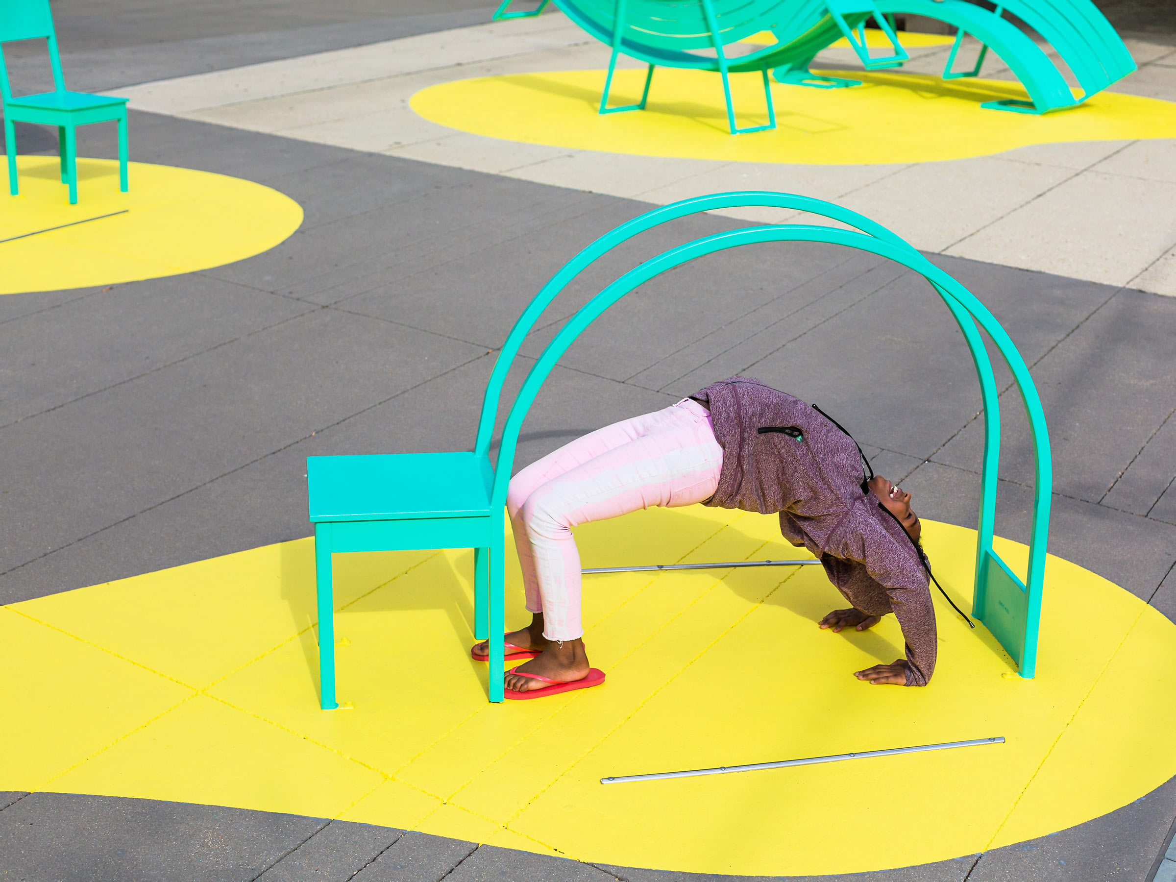 Kid doing backbend under arch of sculptural chair back